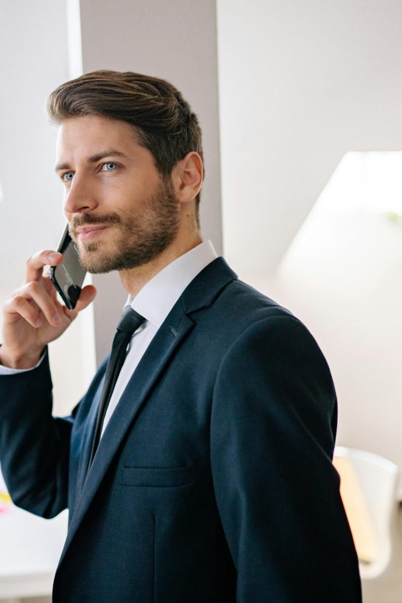 pexels-photo-7691739-7691739 Professional businessman in a suit making a phone call in a modern office setting.